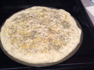 Dough stretched out on 12" pizza plate with rosemary, crushed garlic, olive oil, kosher salt and cracked black pepper