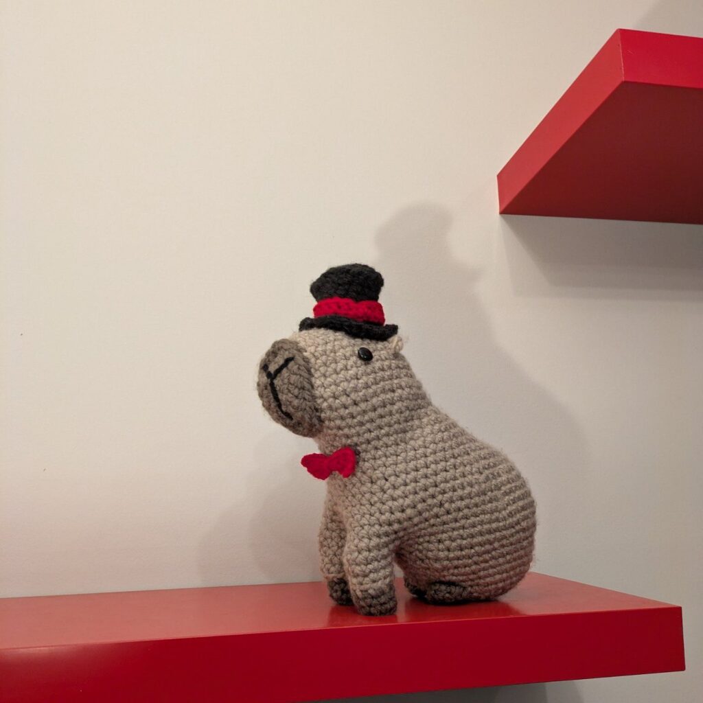 Mr. Capybara facing left posing on floating shelf